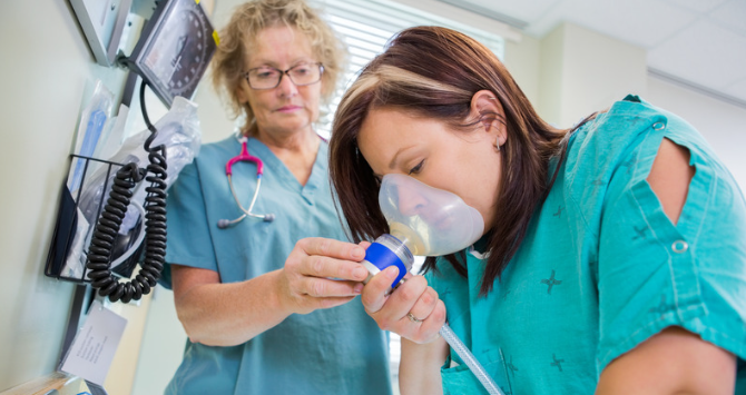 Person in hospital breathing nitrous oxide from a face mask. Nitrous Oxide works as an anaesthetic in the medical industry to reduce pain.